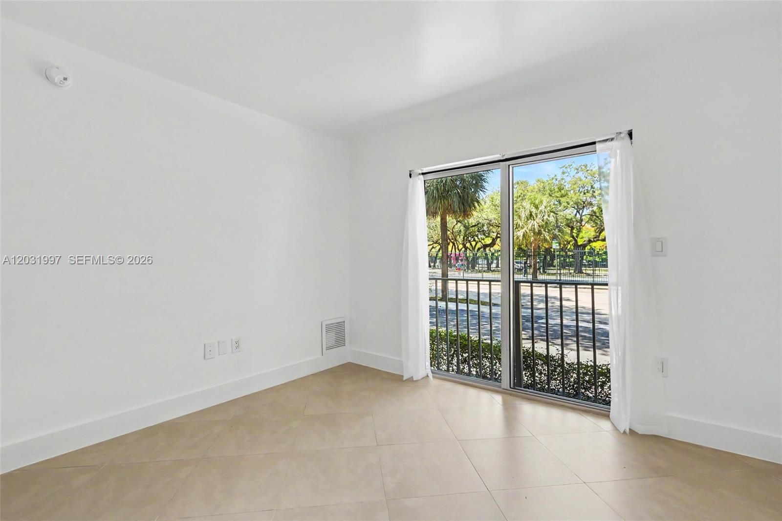 An empty room with white walls, tile flooring, and a sliding glass door to a balcony — 445 SW 11th St # 102, Miami FL 33130, MIAMI, FL