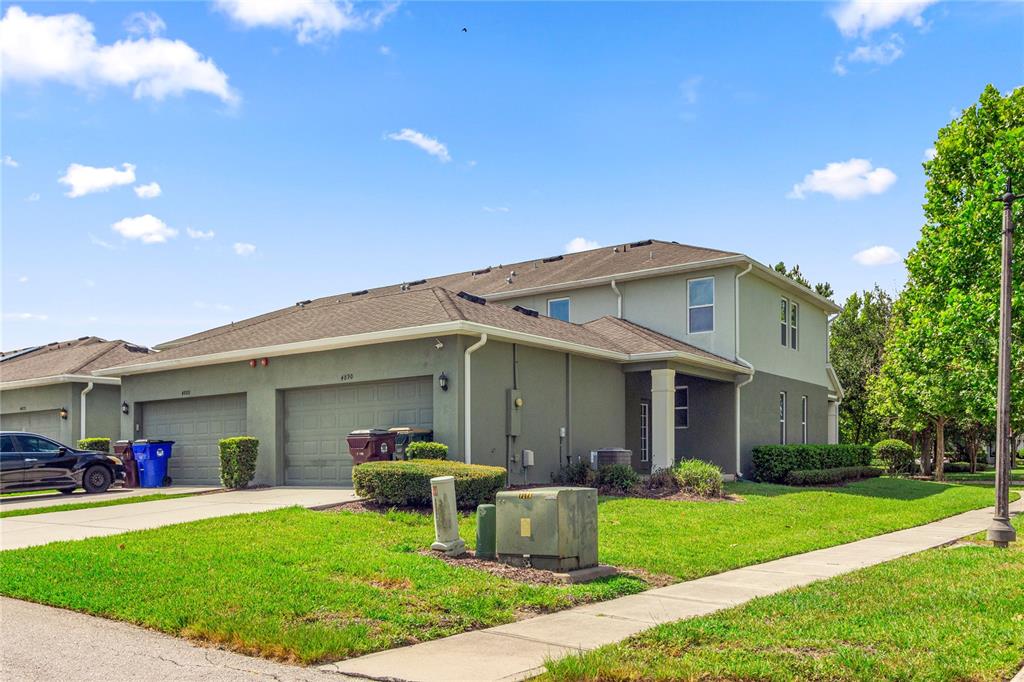 A two-story townhouse with a two-car garage and a green lawn under a blue sky — 4890 NATHAN HALE BOULEVARD, ST CLOUD, FL