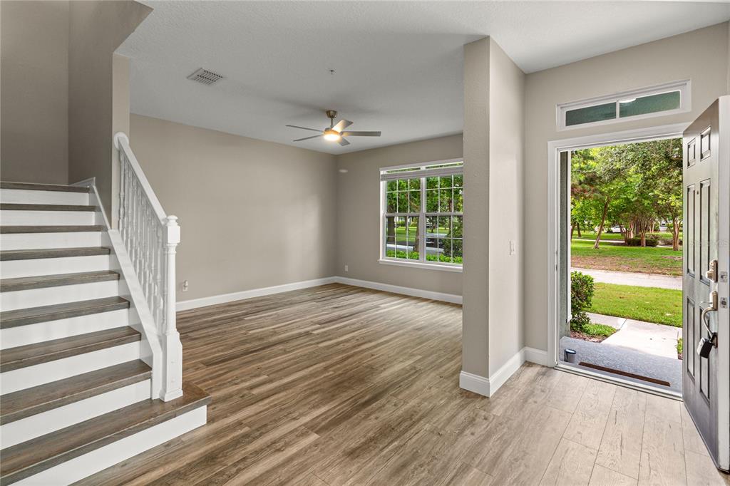 An entryway with wood-look flooring, a staircase with white railings, and an open front door — 4890 NATHAN HALE BOULEVARD, ST CLOUD, FL