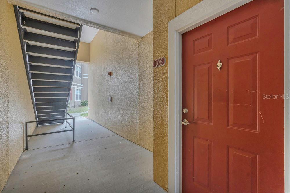 An exterior view shows a red apartment door numbered 108 next to a metal staircase — 8213 CLAIRE ANN DRIVE UNIT 108, ORLANDO, FL