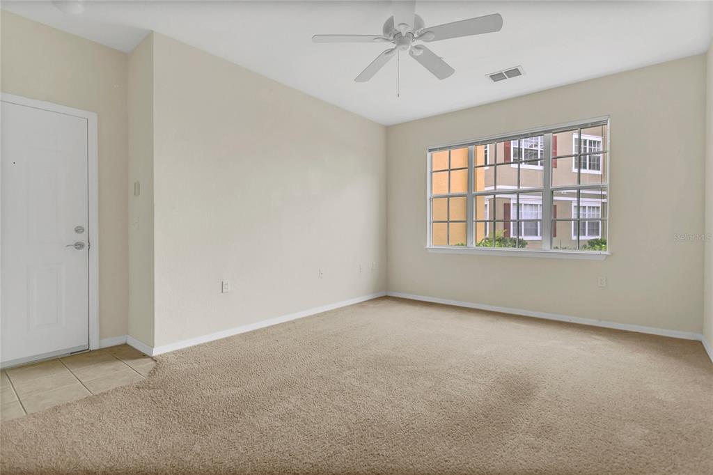 An empty bedroom features beige carpet, a ceiling fan, and a large window — 8213 CLAIRE ANN DRIVE UNIT 108, ORLANDO, FL