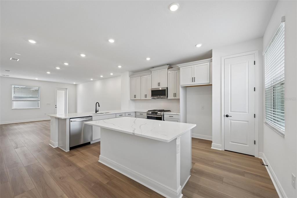 A modern kitchen features white cabinetry, a marble-topped island, and light wood flooring — 8229 SEAFLOWER PARKWAY, BRADENTON, FL