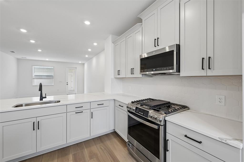 A modern kitchen features white cabinets, stainless steel appliances, and white quartz countertops — 8229 SEAFLOWER PARKWAY, BRADENTON, FL