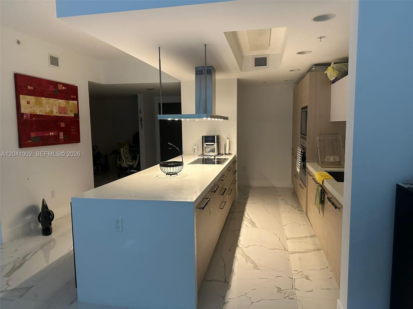 A modern kitchen features a large white island, stainless steel range hood, and marble flooring — 17301 Biscayne Blvd # 206, North Miami Beach FL 33160, NORTH MIAMI BEACH, FL