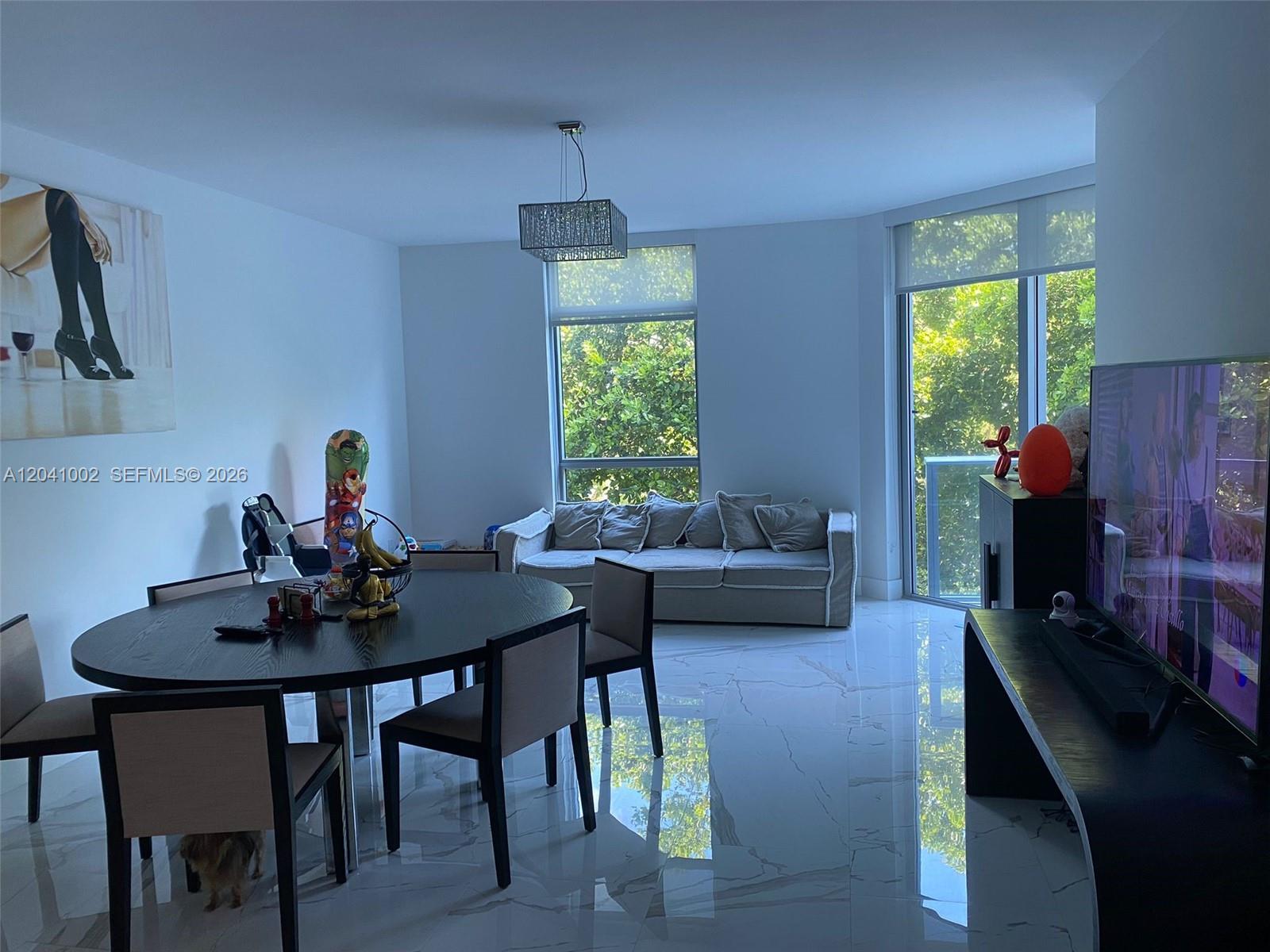A dining area and living space feature white marble floors, large windows, and modern furniture — 17301 Biscayne Blvd # 206, North Miami Beach FL 33160, NORTH MIAMI BEACH, FL