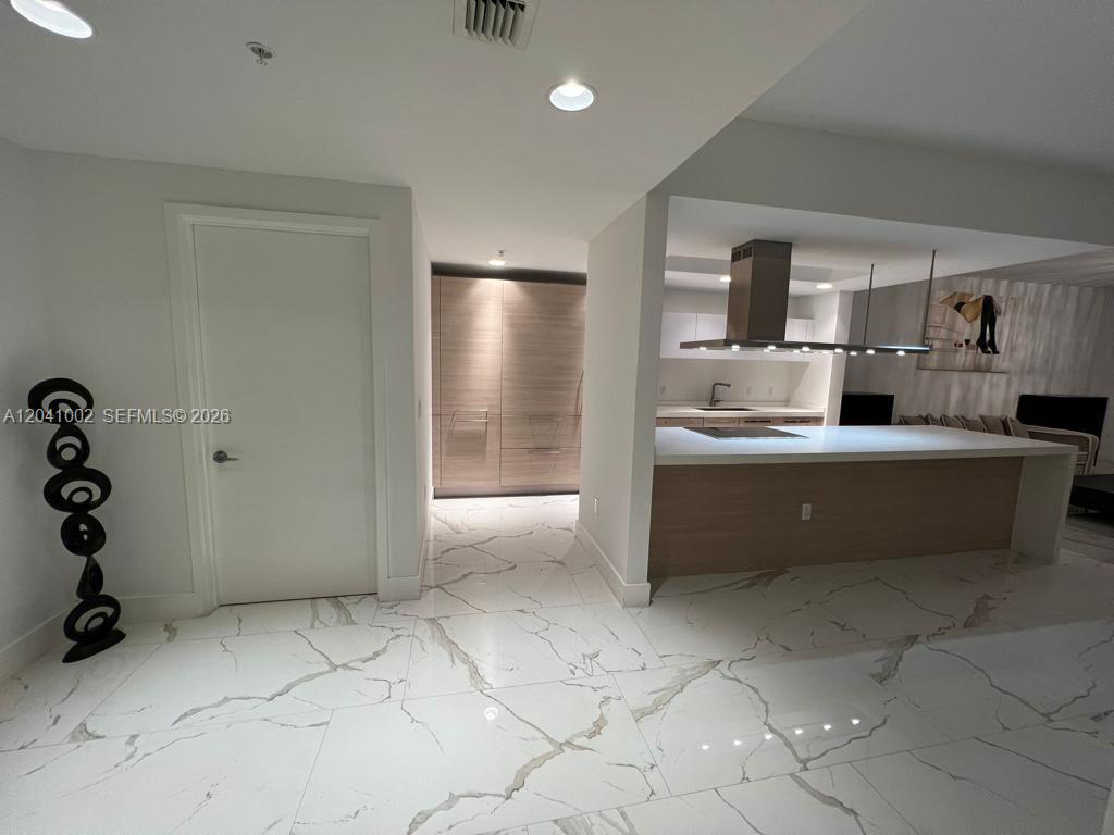 A modern kitchen features a white island, marble-style flooring, and light wood cabinetry — 17301 Biscayne Blvd # 206, North Miami Beach FL 33160, NORTH MIAMI BEACH, FL