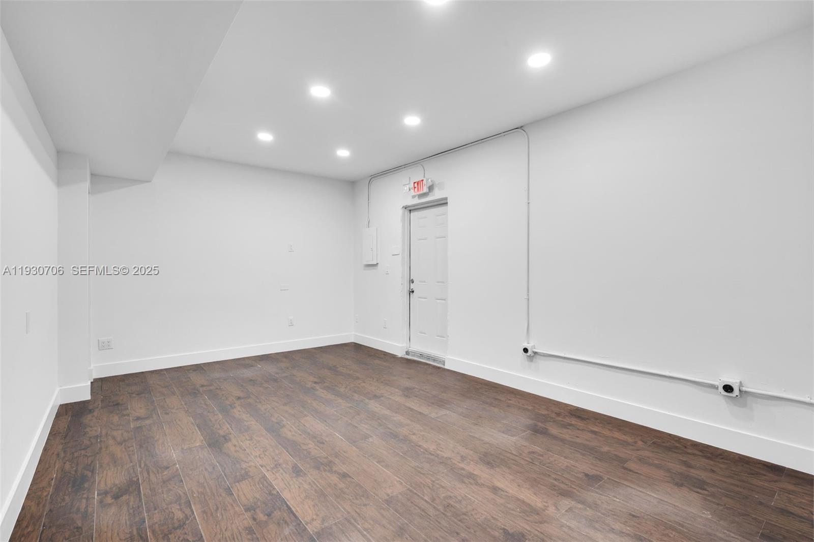 A minimalist room features white walls, recessed lighting, and dark wood-look flooring — 8930 SW 40th St, Miami FL 33165, MIAMI, FL