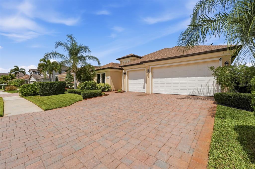 A single-story house with a paved driveway and a three-car garage under a blue sky — 534 CHANTILLY TRAIL, BRADENTON, FL