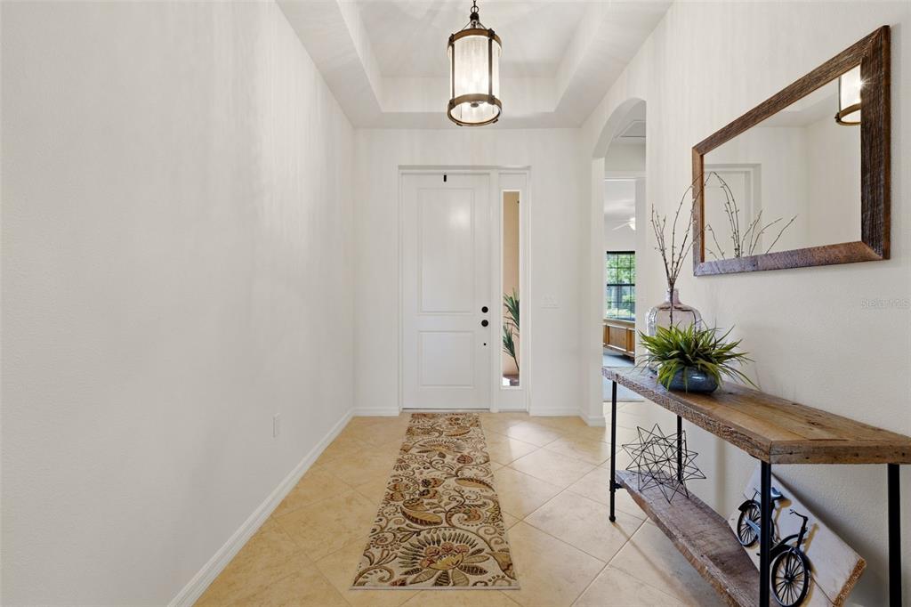 An entryway features tile flooring, a wooden console table, a mirror, and a pendant light — 534 CHANTILLY TRAIL, BRADENTON, FL
