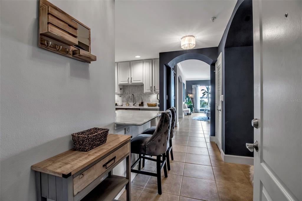 A hallway with a wooden console table leads toward a kitchen and a living area — 808 3RD AVENUE W UNIT 307, BRADENTON, FL