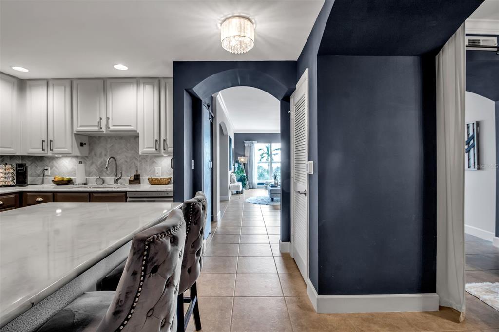 A kitchen with white cabinets and a marble island leads through an arched hallway — 808 3RD AVENUE W UNIT 307, BRADENTON, FL