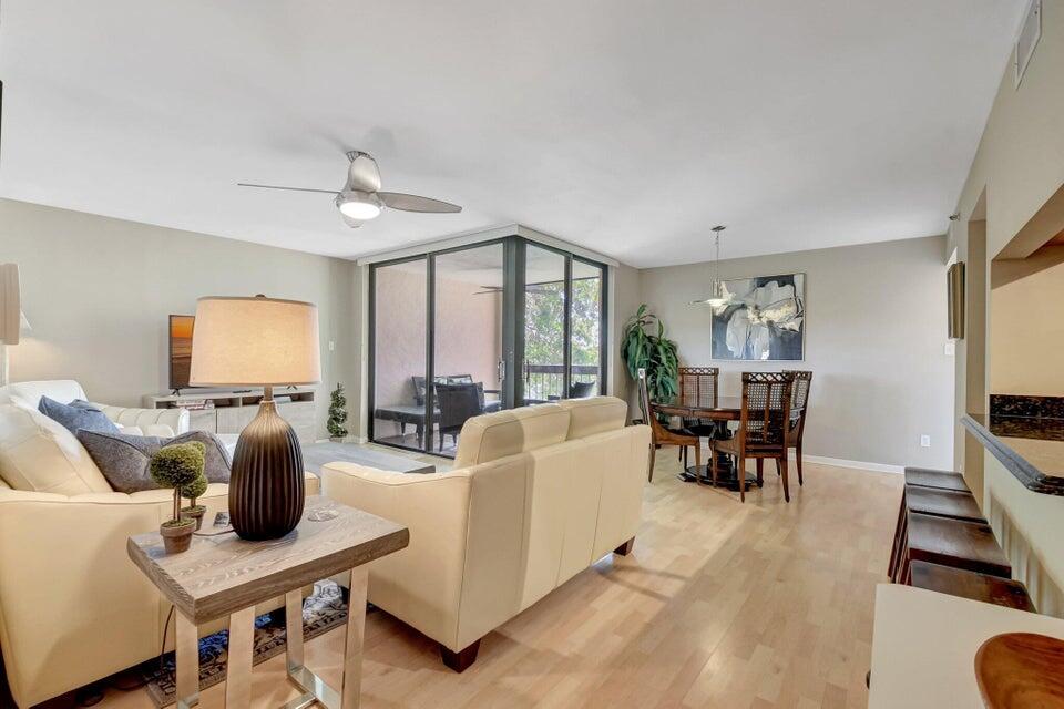 A living and dining area features light wood flooring, white sofas, and a glass-enclosed balcony — 950 Lavers Circle # F309, Delray Beach FL 33444, DELRAY BEACH, FL