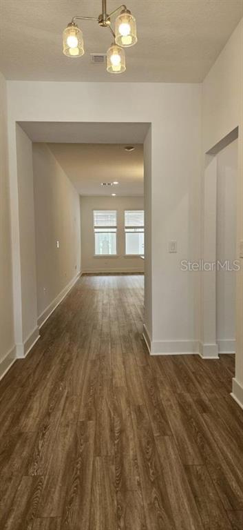 A hallway with wood-look flooring leads toward a bright room with windows and recessed lighting — 13552 AUTUMN HARVEST AVENUE, WINTER GARDEN, FL