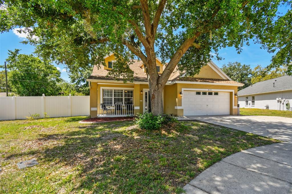 A yellow two-story house with a white garage and a large tree in the front yard — 24231 SATINWOOD COURT, LUTZ, FL