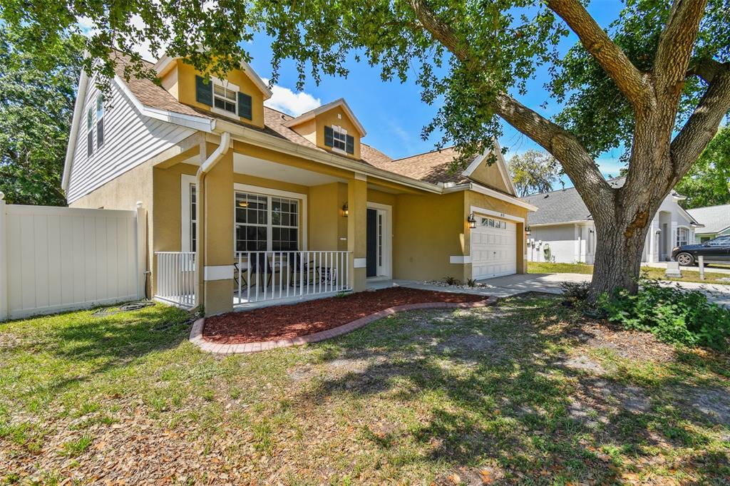 A two-story house with a yellow stucco exterior, a front porch, and a white fence — 24231 SATINWOOD COURT, LUTZ, FL