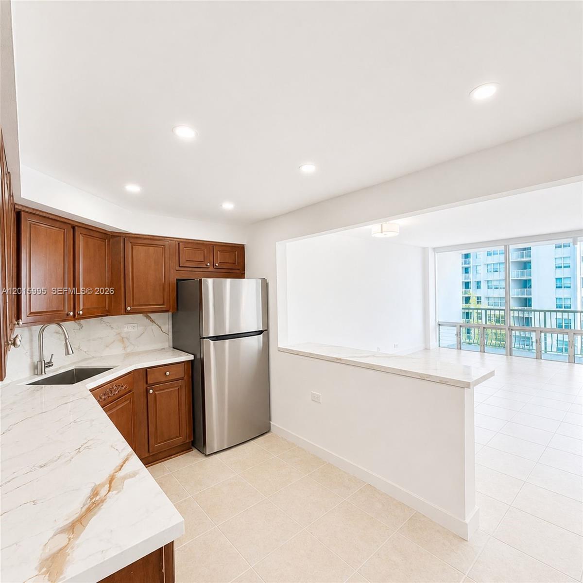 A kitchen with wood cabinets, marble-patterned countertops, and a breakfast bar overlooking a balcony — 1408 Brickell Bay Dr # 1104, Miami FL 33131, MIAMI, FL