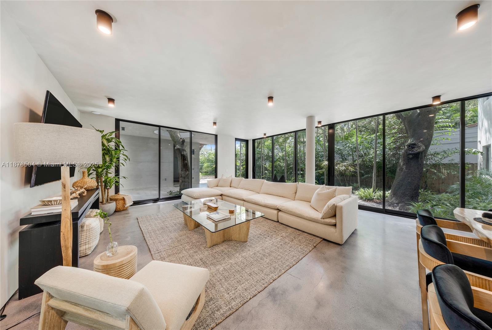 A modern living room features a large sectional sofa, glass coffee table, and floor-to-ceiling windows — 1000 NW 9th Ct, Miami FL 33136, MIAMI, FL