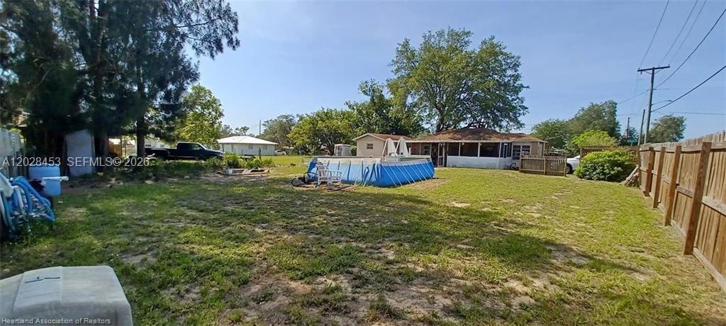 A backyard features a blue above-ground pool, a house with a porch, and a fence — 509 S Florida Ave, Avon Park FL 33825, AVON PARK, FL