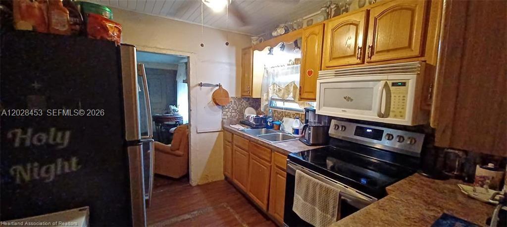 A kitchen features wood cabinets, a black refrigerator, a microwave, and a stainless steel stove — 509 S Florida Ave, Avon Park FL 33825, AVON PARK, FL