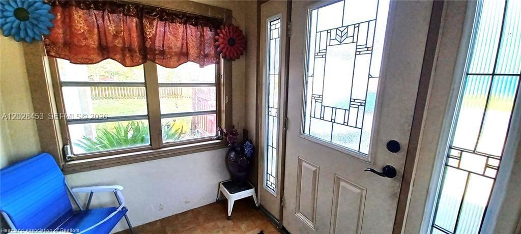 A sunroom features a blue chair, a window with a valance, and a decorative door — 509 S Florida Ave, Avon Park FL 33825, AVON PARK, FL