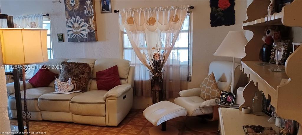 A living room features a light-colored reclining sofa, a matching armchair with ottoman, and curtains — 509 S Florida Ave, Avon Park FL 33825, AVON PARK, FL