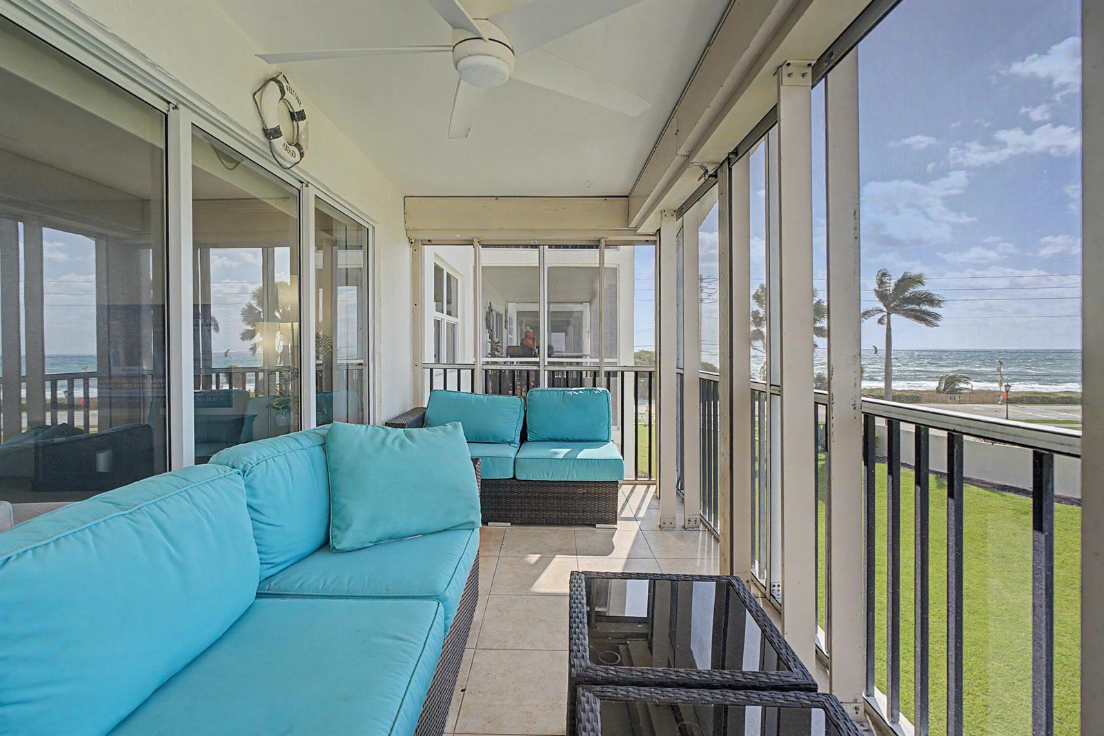 A screened-in balcony features blue cushioned wicker furniture, tile flooring, and an ocean view — 2871 N Ocean Boulevard # C307, Boca Raton FL 33431, BOCA RATON, FL