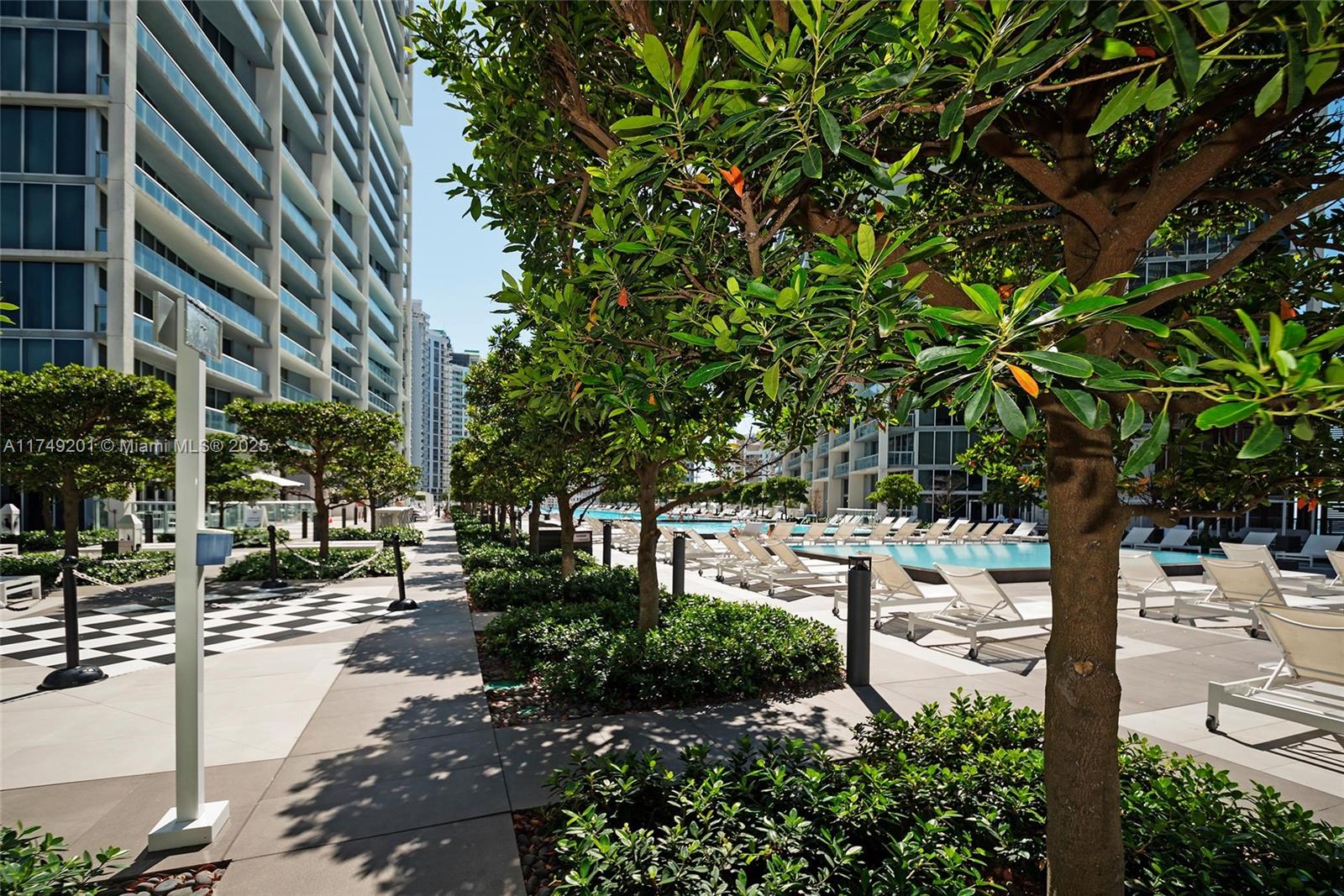 A swimming pool area is surrounded by lounge chairs and tall residential buildings — 485 Brickell Ave # 2603, Miami FL 33131, MIAMI, FL