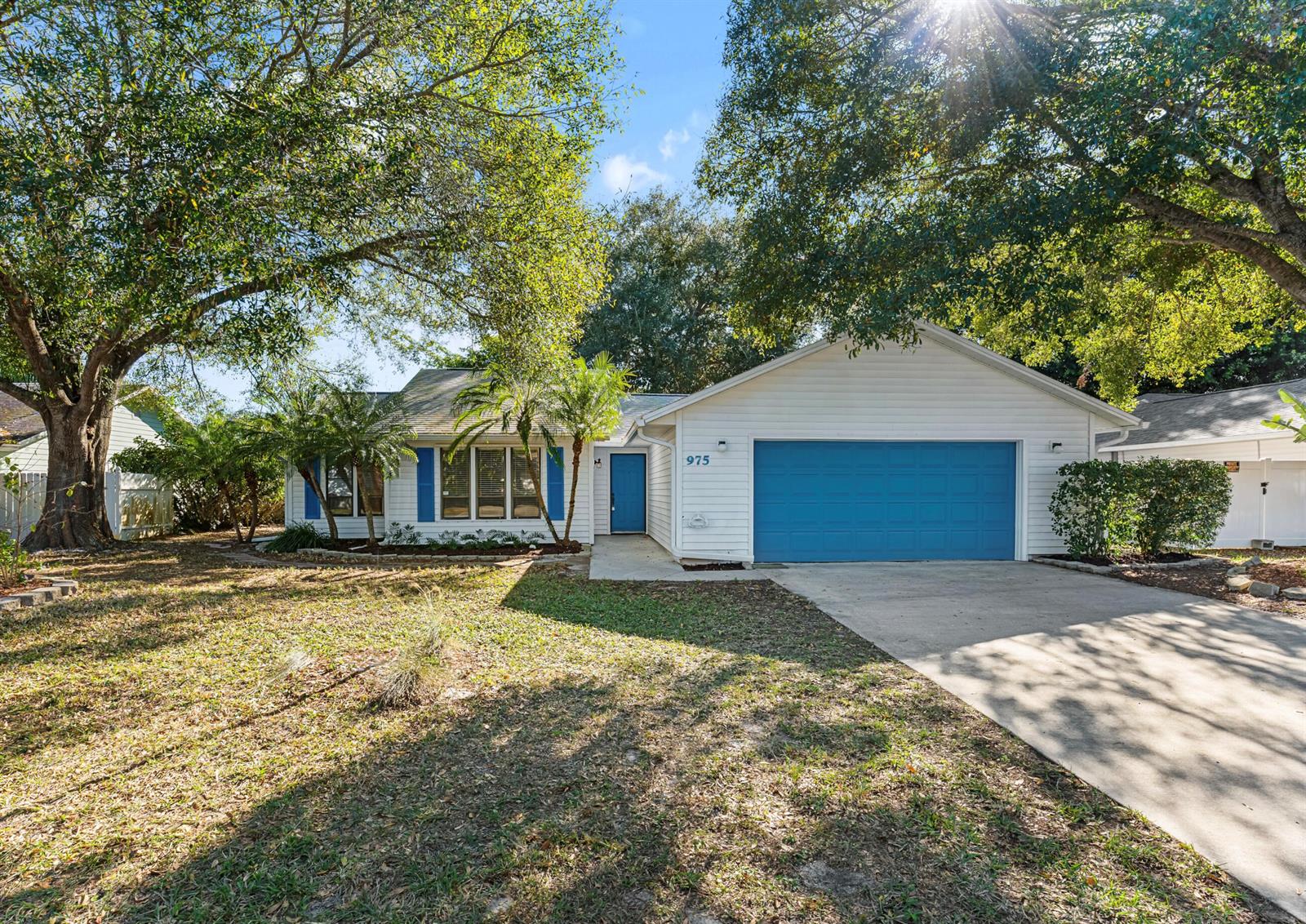 A white single-story house features a blue garage door, blue shutters, and a front lawn — 975 4th Lane, Vero Beach FL 32962, VERO BEACH, FL