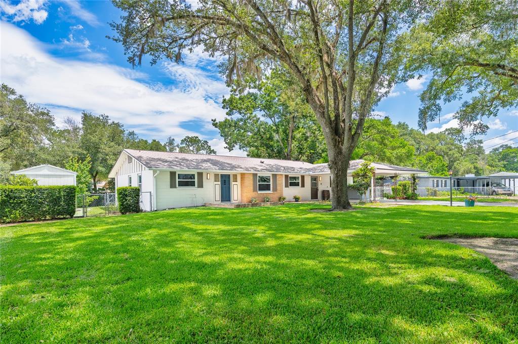A single-story house with a white exterior, a concrete driveway, and a covered carport — 405 OAKHURST STREET, ALTAMONTE SPRINGS, FL