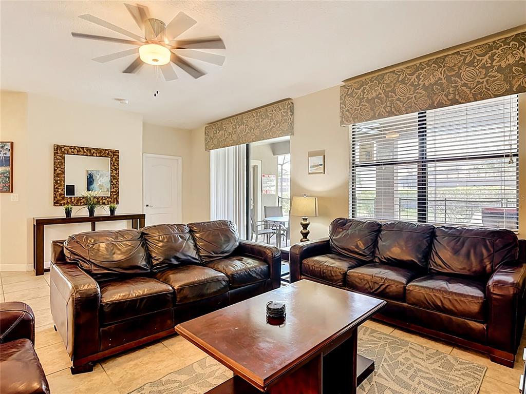 A living room features two dark leather sofas, a coffee table, and a ceiling fan — 1442 MOON VALLEY DRIVE, DAVENPORT, FL