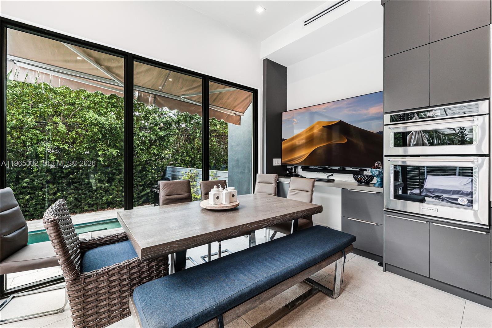 A modern dining area features a wooden table, bench seating, and a wall-mounted television — 640 Fernwood Rd, Key Biscayne FL 33149, KEY BISCAYNE, FL