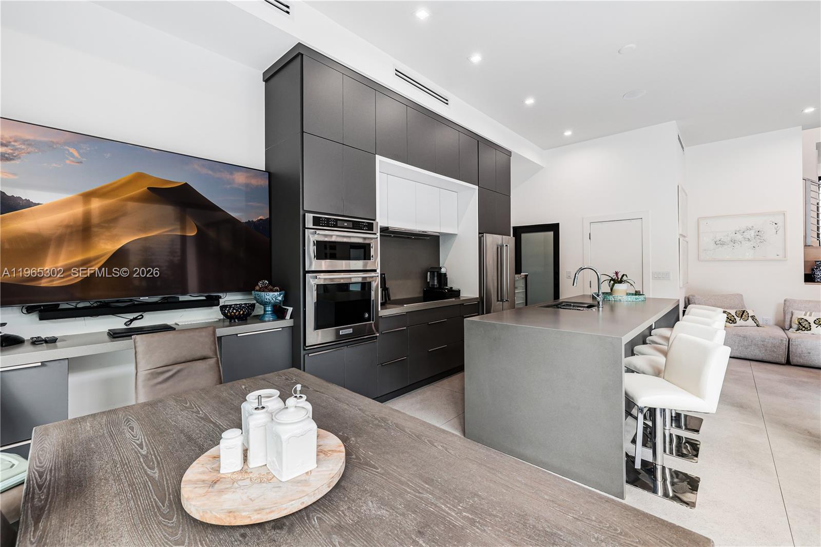 A modern kitchen features dark cabinetry, a large gray island, and an adjacent dining area — 640 Fernwood Rd, Key Biscayne FL 33149, KEY BISCAYNE, FL