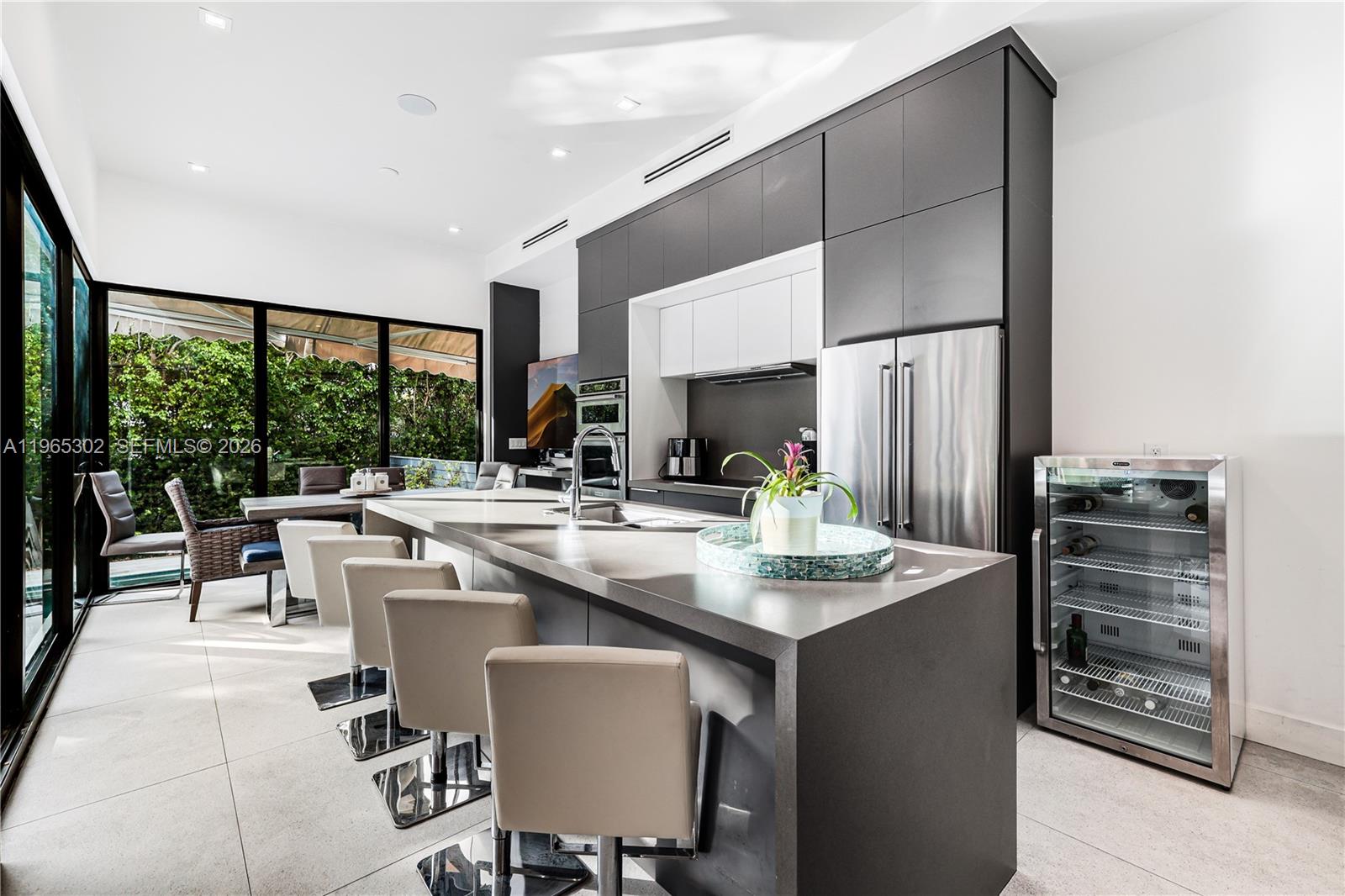 A modern kitchen features dark cabinetry, a large island with bar seating, and floor-to-ceiling windows — 640 Fernwood Rd, Key Biscayne FL 33149, KEY BISCAYNE, FL