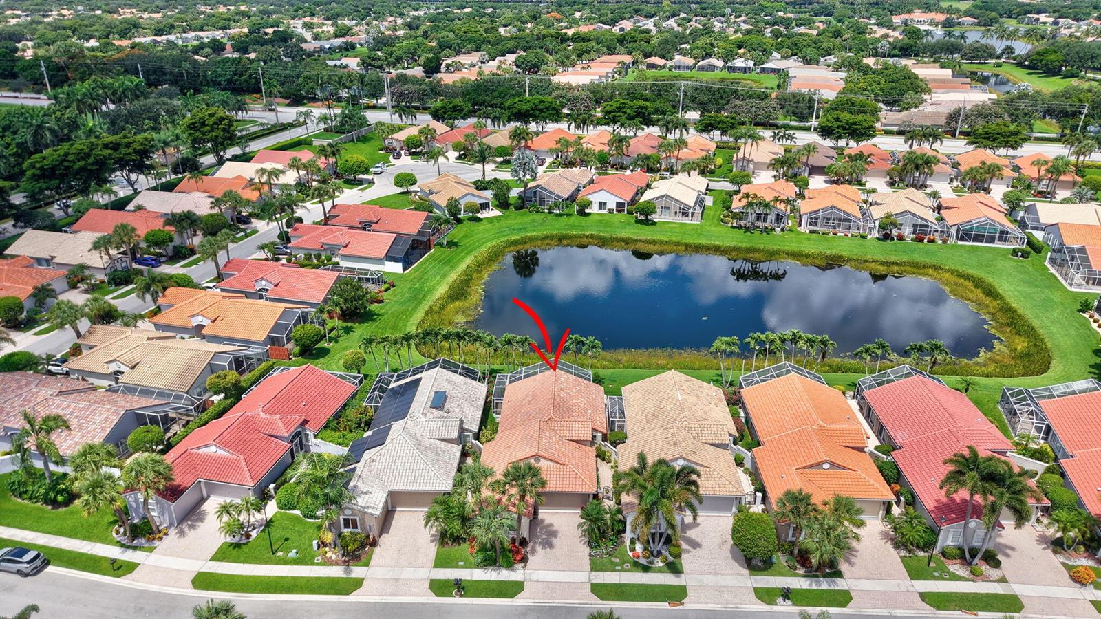 An aerial view shows a residential neighborhood with houses featuring red tile roofs near a lake — 11585 Augustus Drive, Boynton Beach FL 33437, BOYNTON BEACH, FL