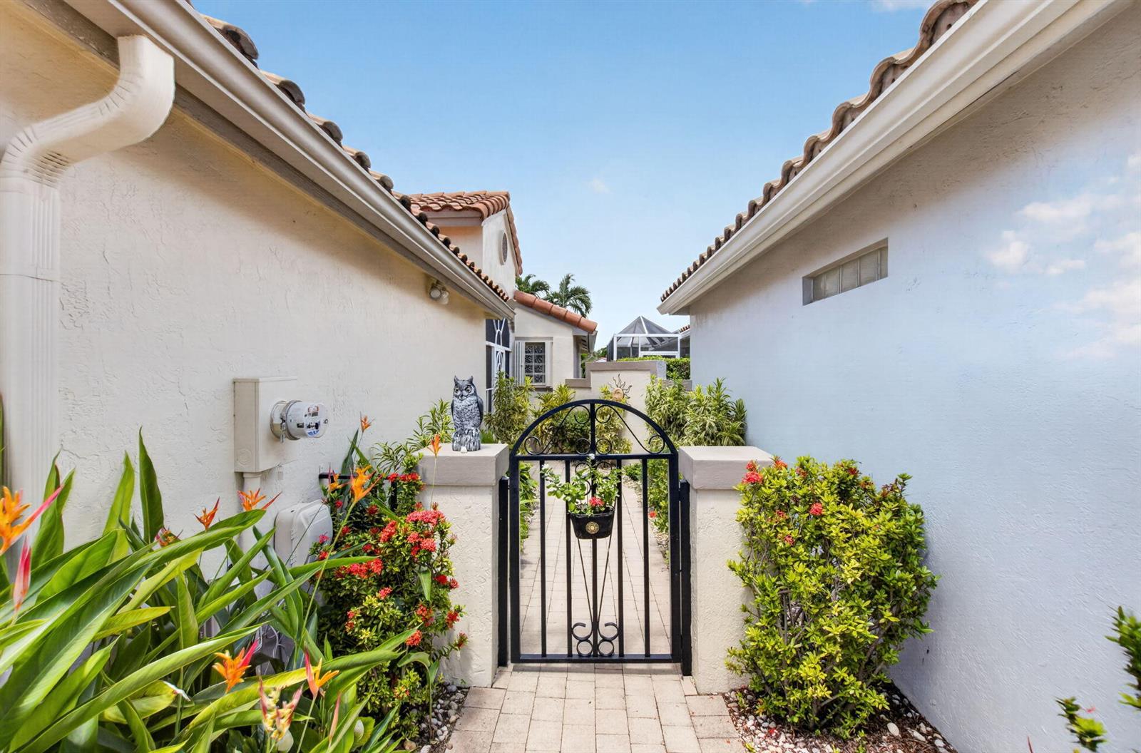 A paved walkway leads through a black metal gate between two stucco exterior walls — 11585 Augustus Drive, Boynton Beach FL 33437, BOYNTON BEACH, FL