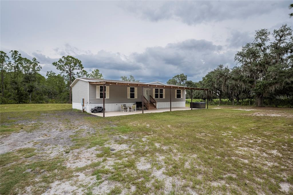 A single-story manufactured home with a covered patio and a hot tub in a yard — 2941 RAWLS ROAD, LAKE WALES, FL