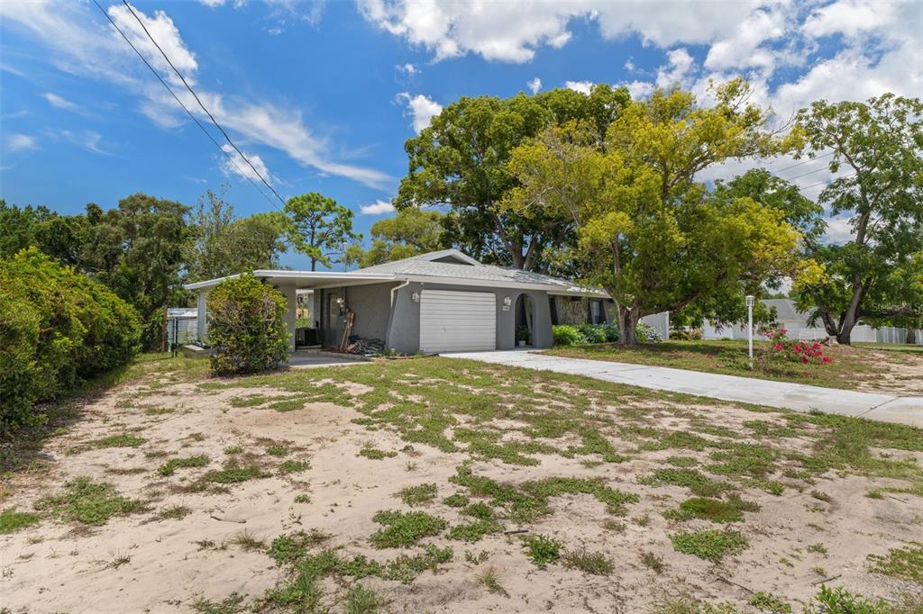 A single-story house with a gray exterior, a garage, and a large tree in front — 6480 INDIAN ROCK COURT, SPRING HILL, FL