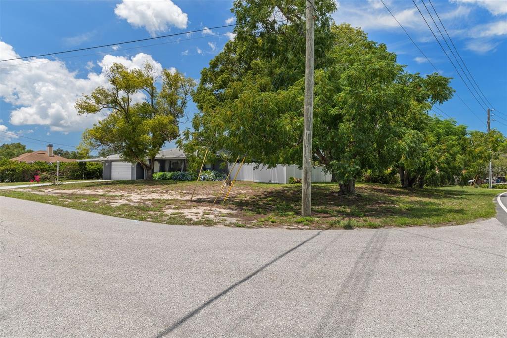 A single-story house with a garage sits behind a large tree on a corner lot — 6480 INDIAN ROCK COURT, SPRING HILL, FL