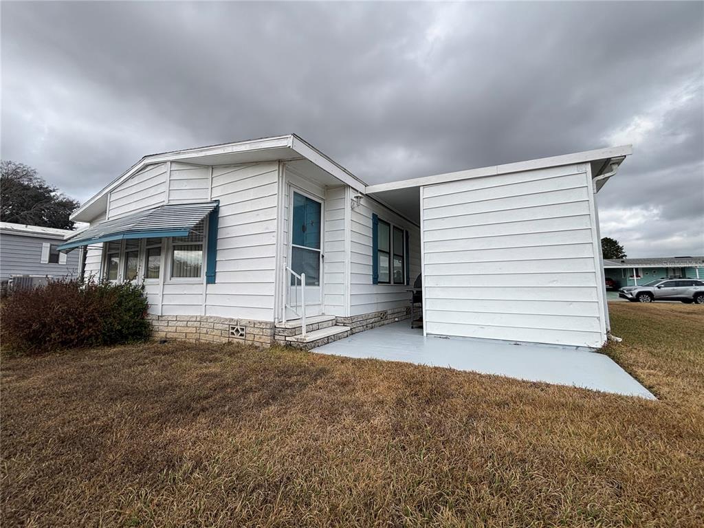 A white mobile home features a covered patio, horizontal siding, and a small brick foundation — 3746 PARWAY ROAD UNIT 1349, ZELLWOOD, FL
