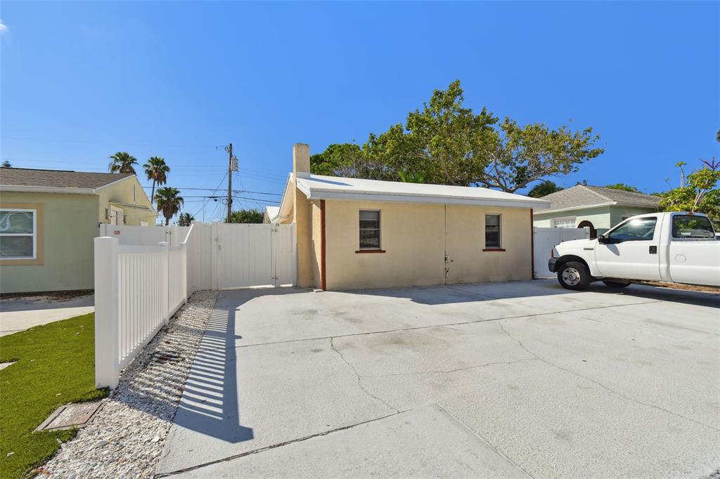 A beige detached garage sits behind a white fence next to a parked white truck — 223 148TH AVENUE E, MADEIRA BEACH, FL