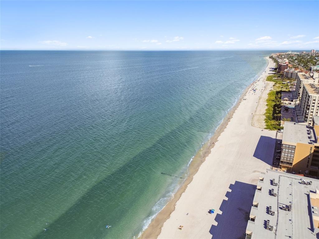 An aerial view of a sandy beach coastline with ocean water and several high-rise buildings — 223 148TH AVENUE E, MADEIRA BEACH, FL