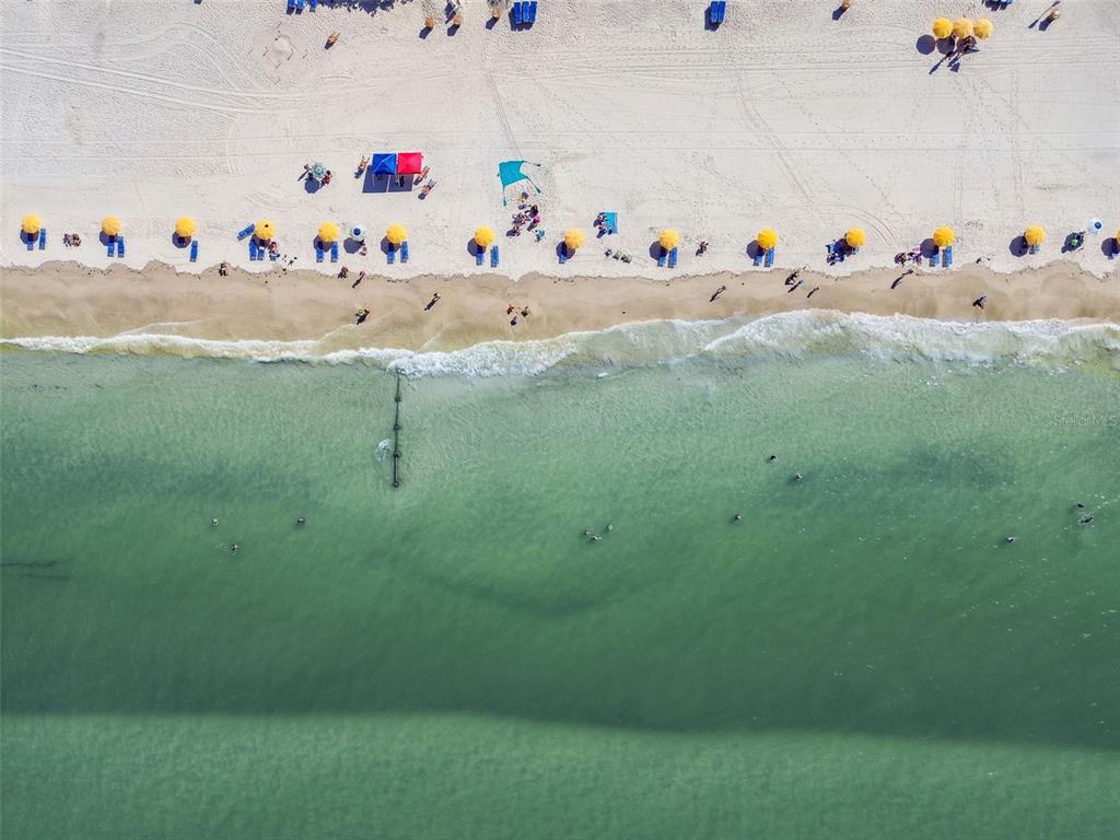 An aerial view of a sandy beach with colorful umbrellas and people swimming in the ocean — 223 148TH AVENUE E, MADEIRA BEACH, FL