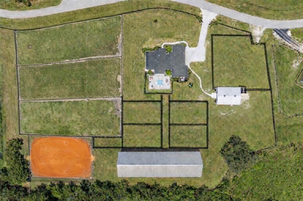 This aerial view shows a residential property with a house, pool, barn, and fenced pastures — 11098 NW 50TH LANE, OCALA, FL