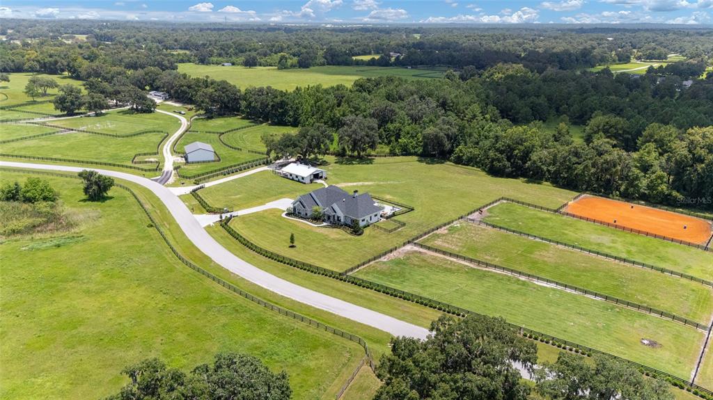 An aerial view shows a house, outbuildings, and fenced pastures on a large rural property — 11098 NW 50TH LANE, OCALA, FL