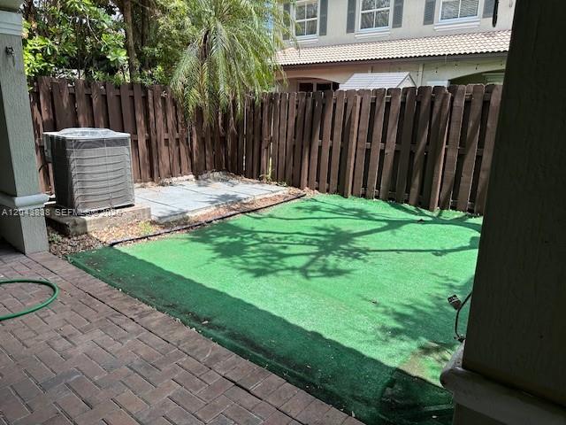 A small backyard features artificial turf, a brick patio, and a wooden privacy fence — 15305 SW 89th Ter # 0, Miami FL 33196, MIAMI, FL