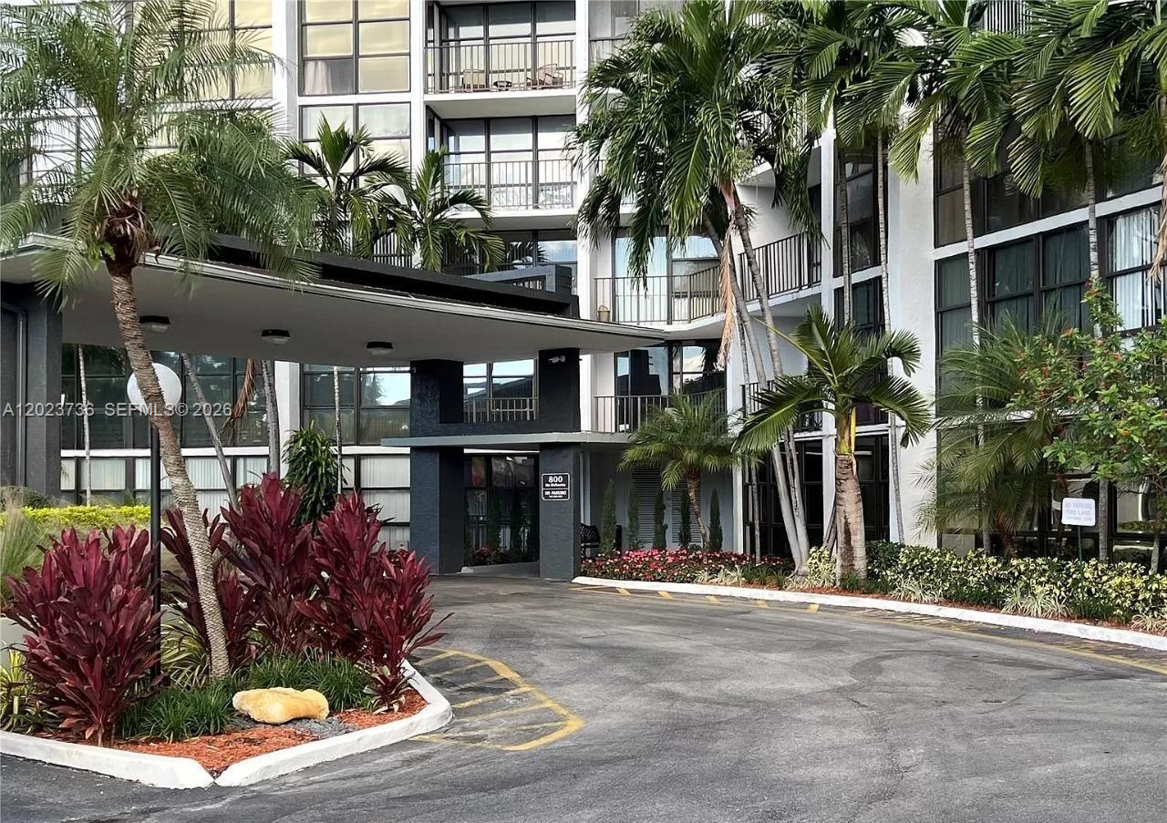 A paved driveway leads to the covered entrance of a multi-story apartment building with landscaping — 800 Parkview Dr # 430, Hallandale Beach FL 33009, HALLANDALE BEACH, FL