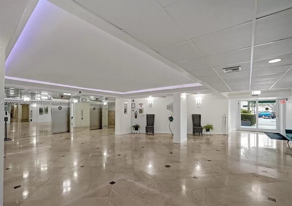 A bright, tiled lobby features two elevators, high-backed chairs, and glass doors leading outside — 800 Parkview Dr # 430, Hallandale Beach FL 33009, HALLANDALE BEACH, FL