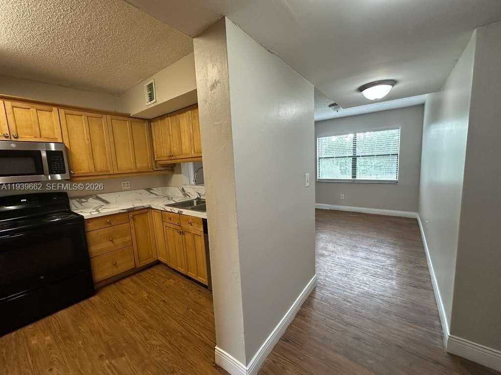 A kitchen with light wood cabinets and a marble-patterned countertop opens to a dining area — 3400 Foxcroft Rd # 115, Miramar FL 33025, MIRAMAR, FL