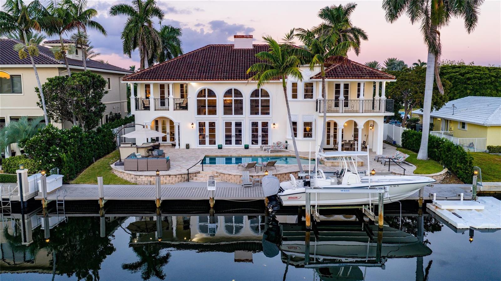 A two-story waterfront house with a pool, patio, and private boat dock at sunset — 2833 NE 32nd Street, Lighthouse Point FL 33064, LIGHTHOUSE POINT, FL