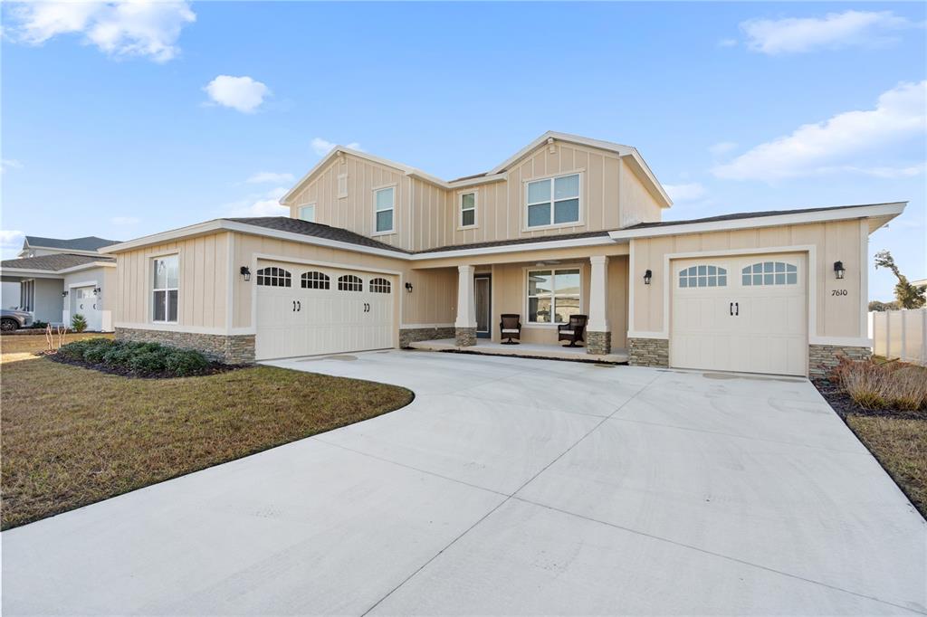 A two-story suburban house with a beige exterior, stone accents, and a concrete driveway — 7610 SW 60TH STREET, OCALA, FL